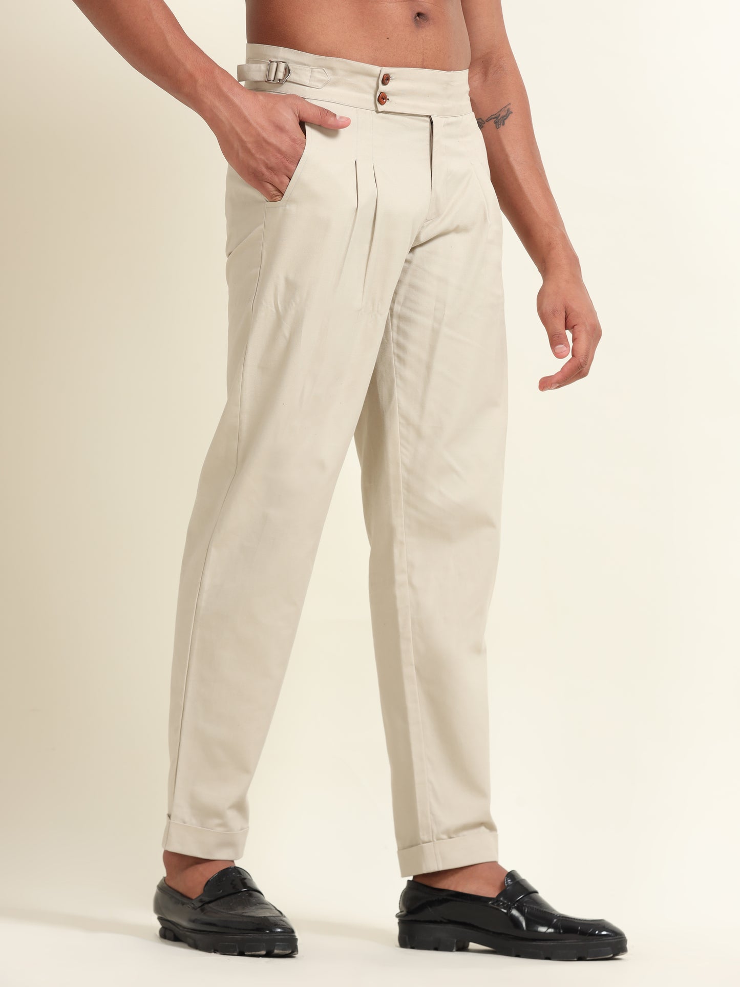 Close-up of double pleats on beige straight fit pants, highlighting the high-quality craftsmanship and design